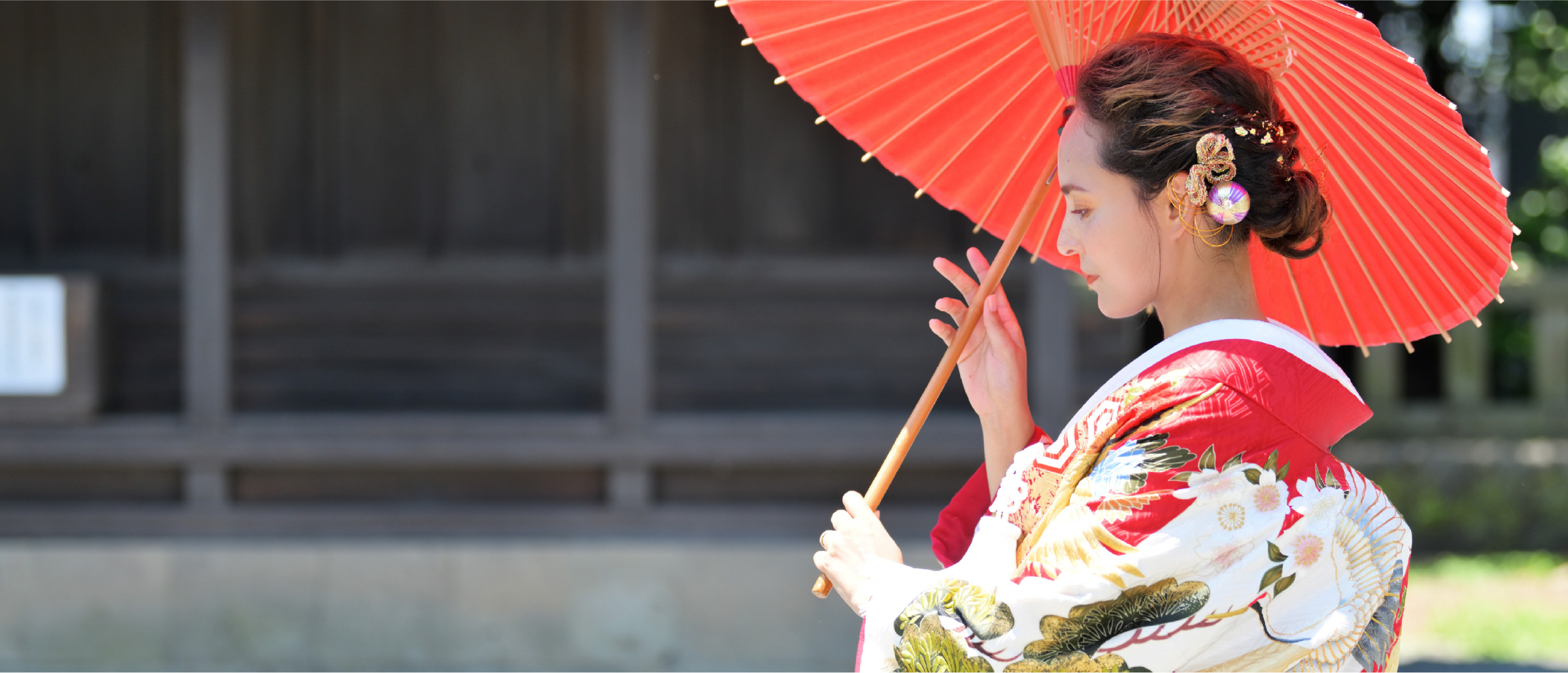 A woman holding a red parasol, dressed in a beautiful kimono