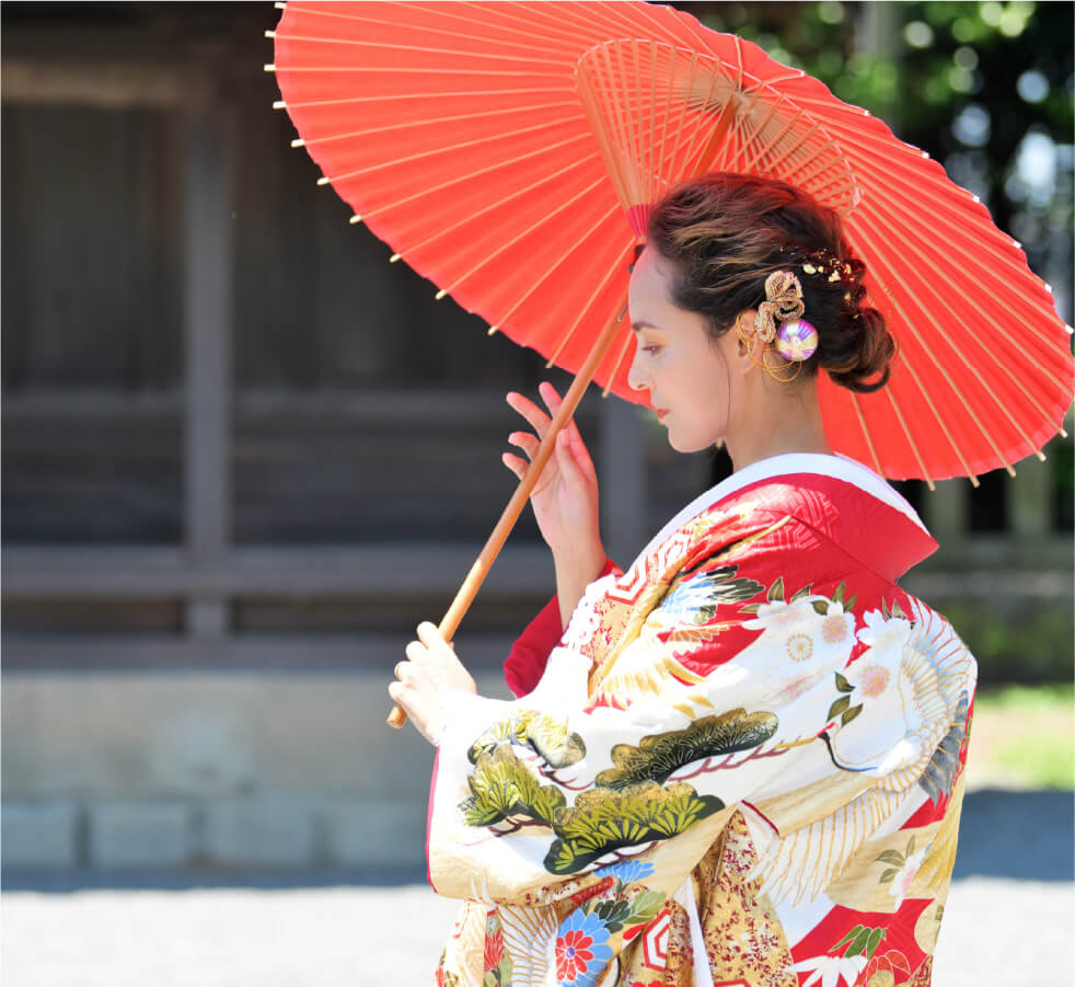 A woman holding a red parasol, dressed in a beautiful kimono