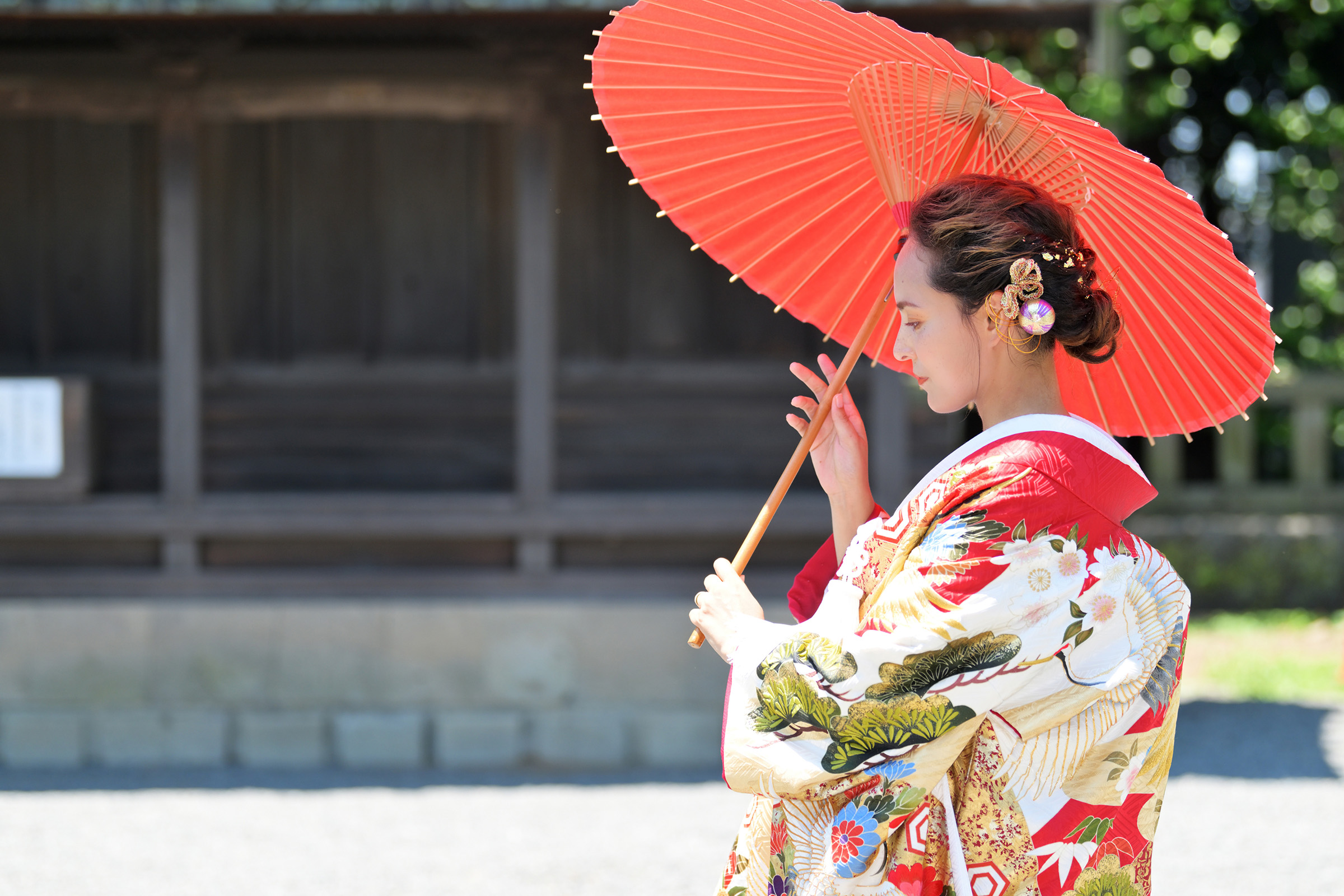 A woman in a red kimono holds a red parasol