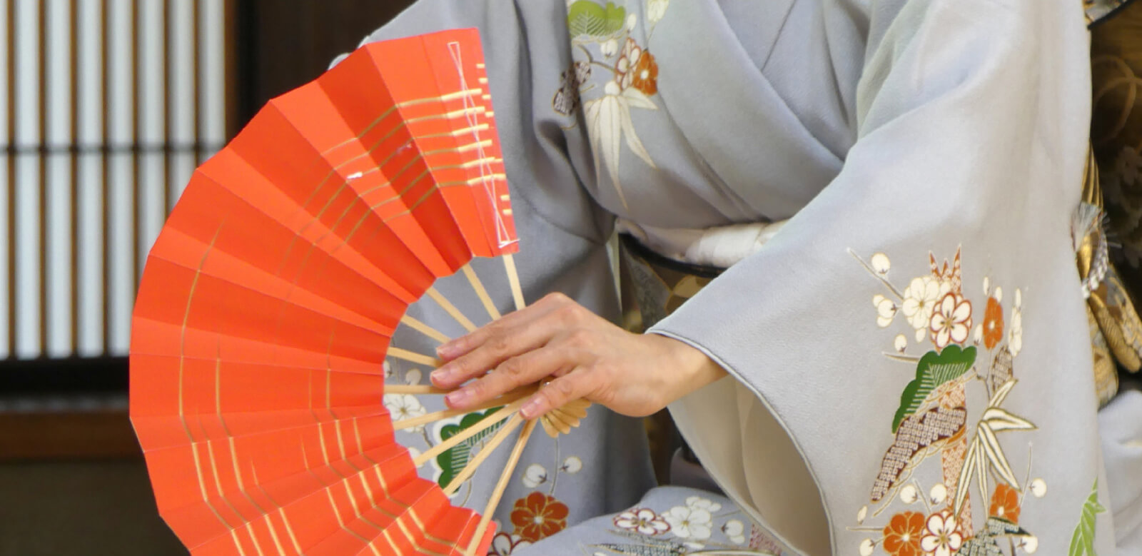 A gaisha dressed in kimono holding a fan